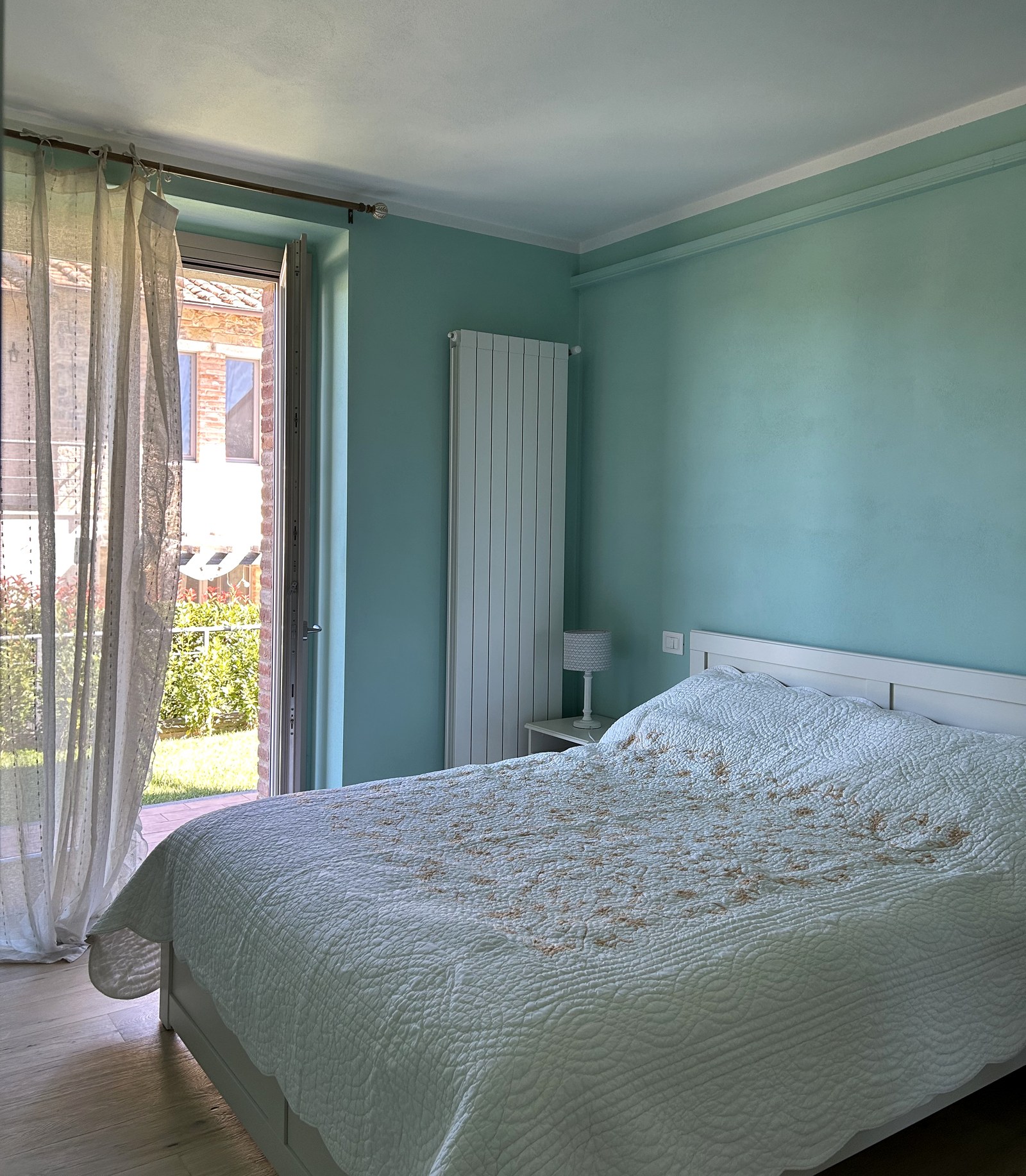 The second bedroom with sage green walls and the door open to the garden